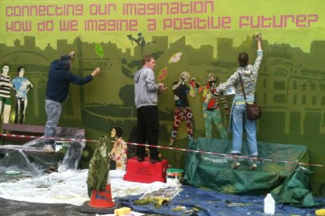 Young people painting a mural. It reads 'Connecting our imagination, how do we imagine a positive future?'